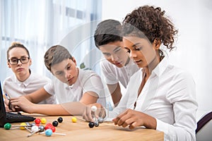 young multicultural students picking molecular model
