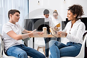 young multicultural teen students studying together and holding cups