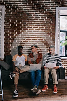 young multicutural businessmen sitting on sofa