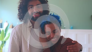 Young multiethnic Arabian man and African American woman hugging stands in home