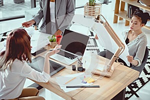 young multiethnic architects with digital devices and blueprints working photo
