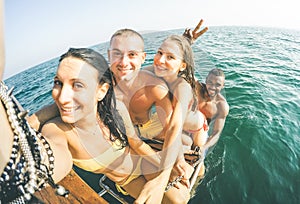 Young multiethnic friends taking selfie after swimming on sailing boat