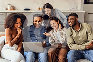 young multiethnic friends watching funny comedy movie on laptop indoors