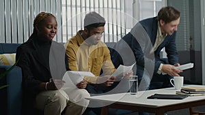 Young multiracial adults in businesswear sitting and reading paperwork in office