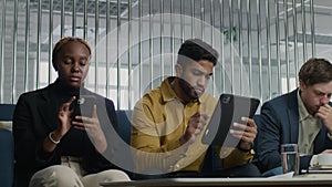 Young multiracial adults in businesswear sitting and using technology in office