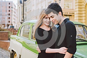 Young multiracial couple, male and female lovers heterosexual people students. Beautiful models posing standing near a retro car