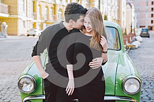 Young multiracial couple, male and female lovers heterosexual people students. Beautiful models posing standing near a retro car
