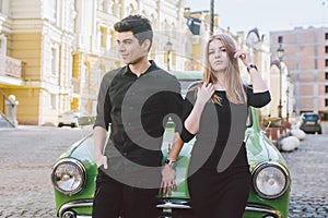 Young multiracial couple, male and female lovers heterosexual people students. Beautiful models posing standing near a retro car