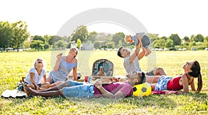 Young multiracial families having fun playing with kids at pic nic garden party - Multiethnic joy and love concept photo