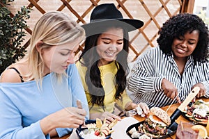 Young multiracial friends having breakfast outdoors in restaurant - Focus in asian girl face
