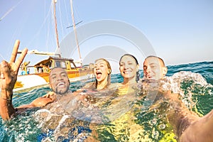 Young multiracial friends taking selfie and swimming on sailing boat tour