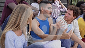 Young multiracial group of friends having fun with mobile smartphone while sitting on urban stairs