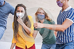 Young multiracial people having fun wearing safety mask outdoor in the city - Focus on african girl face