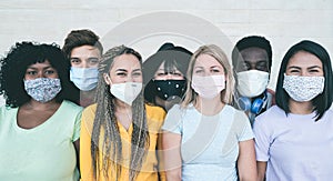 Young multiracial people wearing protective masks during coronavirus outbreak - Social distance between friends concept - Main