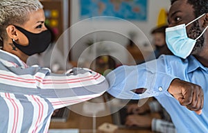 Young multiracial workers wearing face mask doing new social distance greetings bumping elbows inside co-working space photo