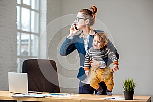Multitasking businesswoman with her son working at the office photo