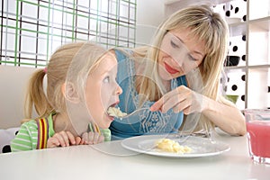 Young mum feeds the daughter with a potato