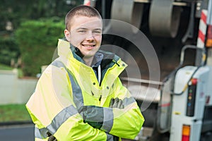 Young municipal garbage collector near garbage truck photo