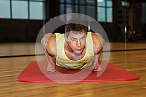 Young muscle man doing push ups in gym