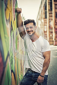 Young muscle man leaning on graffiti wall