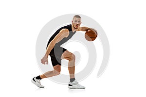 Young muscled man, basketball player practicing with ball isolated on white studio background. Sport, motion, activity