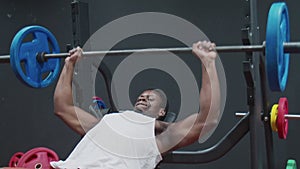 Young muscular afro man exercising bench press chest on the bench with barbell