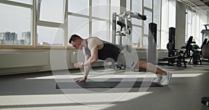 Young muscular athlete works out in a modern gym making push ups exercises