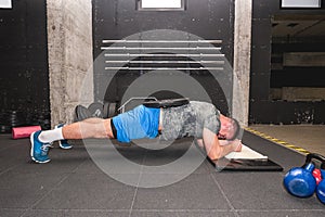 Young muscular attractive and active man workout plank exercise in the gym for strength and conditioning with barbell weight plate