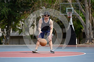 Young muscular basketball player dribbling a ball on an outdoor court
