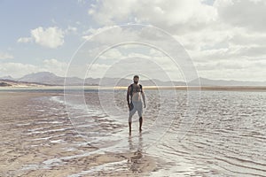Young muscular bearded man standing on the sea shore at sunrise. Side portrait of healthy young bearded man running at