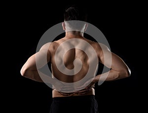 Young muscular body sport man holding sore low back waist with his hands suffering pain