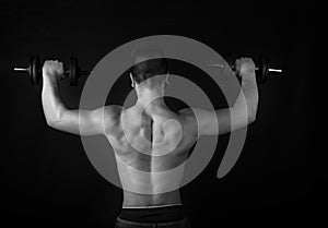 Young muscular fitness guy doing weights on black and white background