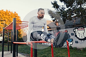 Young muscular good looking man working out on his abs using the horizontal ladder and parallel bars station, street workout