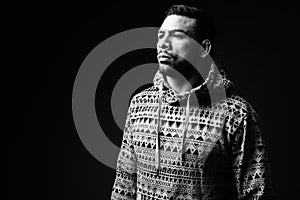 Young muscular Hispanic man against black background