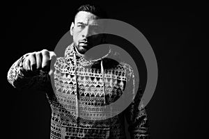 Young muscular Hispanic man against black background