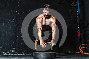 Young muscular man with big sweaty muscles doing push ups workout training with jump his hand above the barbell weight plate on th