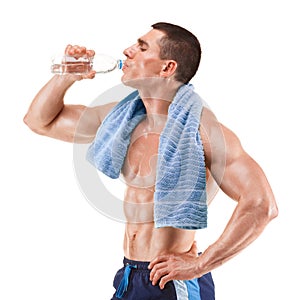 Young muscular man with blue towel over neck, drinking water, isolated on white