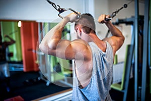 young, muscular man, bodybuilder working out in gym