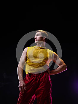 a young muscular man in a bright outfit poses in a pretentious pose, photo