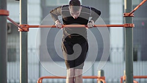 Young muscular man doing Muscle Up exercise on bar outdoors