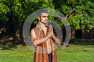 Young muscular man doing yoga on grass wearing a cap