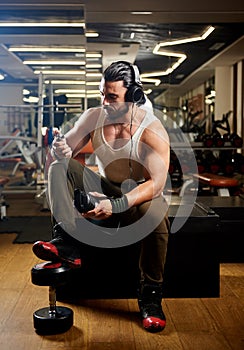Young muscular man exercising in gym and listening music