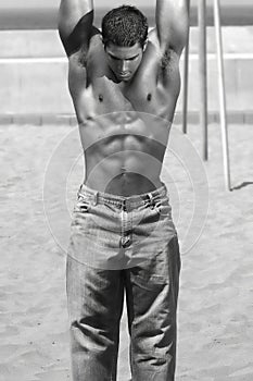 Young muscular man hanging from bar