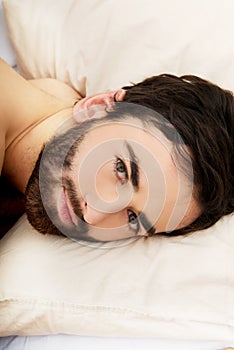 Young muscular man lying in bed.