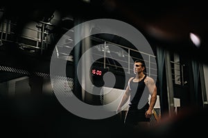 Young muscular man with perfect beautiful body wearing sportswear standing in modern dark gym.