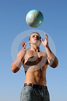 Young muscular man playing with a terrestrial globe