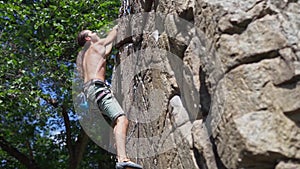 Young muscular man rock climber climbing on tough sport route, searching, reaching and gripping hold.