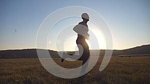 Young muscular man running through field with beautiful landscape at background. Male athlete trains in nature. Guy jogs