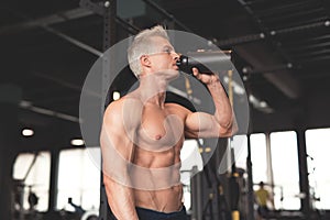 Young muscular man showing his perfect body. Man drinking from a cocktail shaker with the protein. Toned image