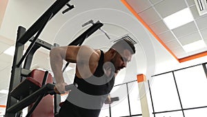 Young muscular man during training in the gym performs pushups on the bars